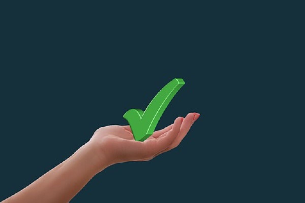 Hand holding a green tick arrow